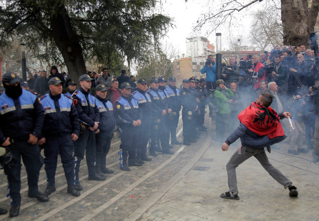 A protester throws a firecracker in front of unimpressed police during a protest outside the Albanian parliament in Tirana, Albania, 05 March 2019. Opposition MPs have resigned from their parliamentary mandates, and protesters demand the government's resignation and early elections. (Photo by Malton Dibra/EPA/EFE)