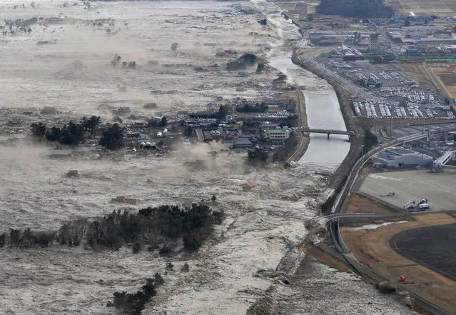 In this March 11, 2011 file aerial photo, an earthquake-triggered tsunami sweeps shores along Iwanuma, Miyagi Prefecture, northeastern Japan. (Kyodo News via AP Photo)