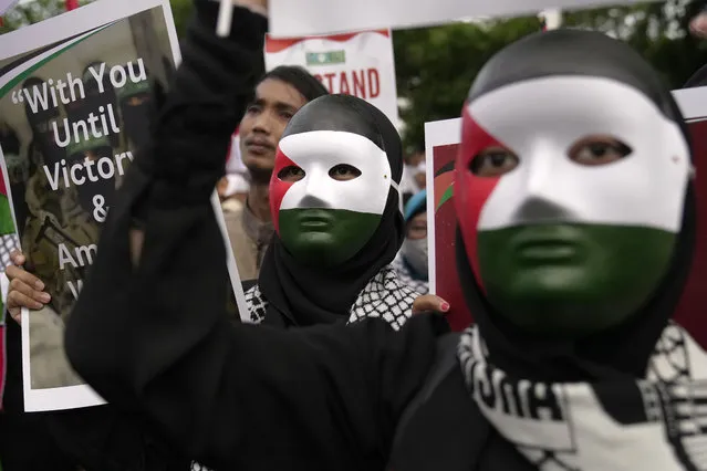 Protesters wearing masks with the colors of Palestinian flag hold posters during a rally in support of the Palestinians outside the U.S. Embassy in Jakarta, Indonesia, Saturday, January 13, 2024. Thousands of people attended the rally ahead of the 100th day since the war between Israel and Hamas in Gaza. (Photo by Dita Alangkara/AP Photo)