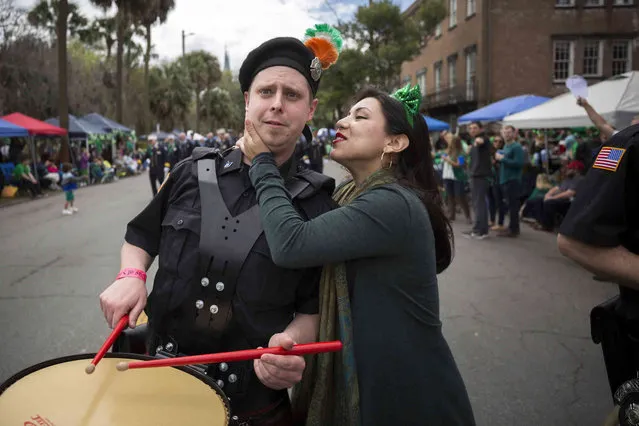 A Yonkers Fire Pipe and Drum drummer reacts to being kissed by Kayla DeJesus, right, while he marches in the 195-year-old Savannah St. Patrick's Day parade, Saturday, March 16, 2019, in Savannah, Ga. (Photo by Stephen B. Morton/AP Photo)