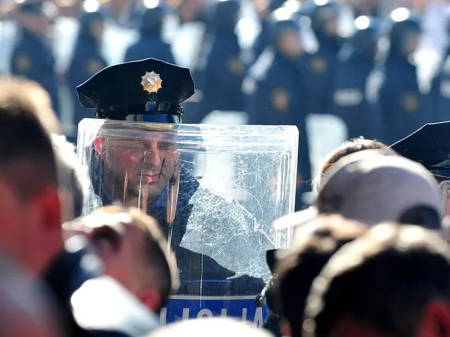 Bosnian policemen are seen while protestors throw stones at a local government building in the Northern-Bosnian town of Tuzla on February 7, 2014. Protesters angry over Bosnia's devastated economy broke into a government building in northeastern Tuzla on Friday, destroying furniture and throwing television sets through windows. (Photo by Elvis Barukcic/AFP Photo)