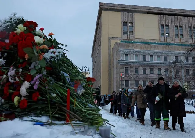 People walk to lay flowers at the Solovetsky Stone monument to the victims of political repressions to honour the memory of Russian opposition leader Alexei Navalny in Moscow, Russia on February 17, 2024. (Photo by Reuters/Stringer)