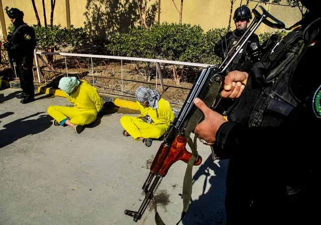 Members of Iraq's Special Weapons and Tactics Team ) stand guard over blindfolded suspected members of the al-Qaida-linked Islamic State of Iraq and the Levant at the federal police headquarters in Basra, on February 11, 2014. Security forces arrested 14 suspected al-Qaida members during recent security operations in Basra. (Photo by Nabil al-Jurani/Associated Press)