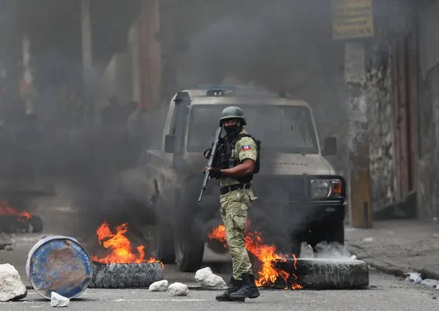 A police officer stands guard near a burning barricade set up in protest against the government and calling for the resignation of Prime Minister Ariel Henry, in Port-au-Prince, Haiti on February 5, 2024. (Photo by Ralph Tedy Erol/Reuters)