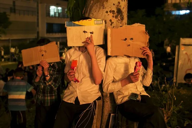 Ultra-Orthodox Jewish children hold cardboard in front of their faces as they watch bonfires during celebrations for the Jewish holiday of Lag Ba'Omer in Bnei Brak May 6, 2015. (Photo by Baz Ratner/Reuters)
