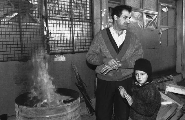 A father and his son stand in front of a destroyed store warming themselves up on an open fire in downtown Sarajevo, Wednesday, October 14, 1992. For nearly four years, Sarajevo’s roughly 350,000 residents were trapped and faced daily shelling and sniper attacks. Cut off from regular access to electricity, heat and water, they survived on limited humanitarian aid from the United Nations while drinking from wells and foraging for food. (Photo by Hansi Krauss/AP Photo)