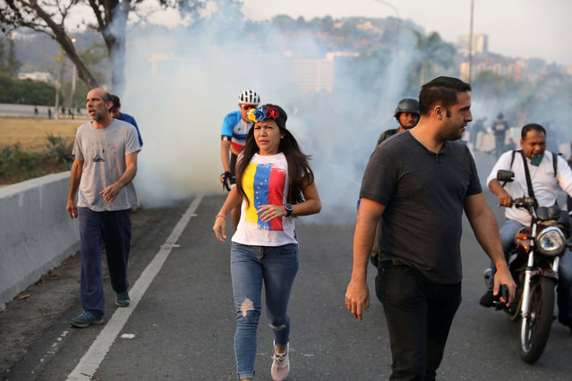 People run away from tear gas near the Generalisimo Francisco de Miranda Airbase “La Carlota”, in Caracas, Venezuela April 30, 2019. (Photo by Manaure Quintero/Reuters)