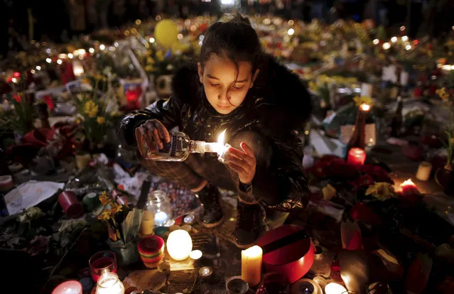 A girl lights candles at the Place de la Bourse as people pay tribute to the victims of Tuesday’s bomb attacks in  Brussels, Belgium on March 27, 2016. (Photo by Christian Hartmann/Reuters)