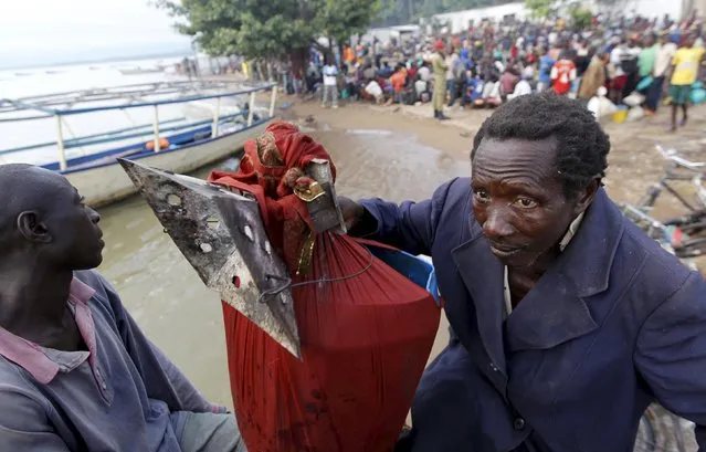 A Burundian refugee carries his belongings as he boards a boat on the shores of Lake Tanganyika in Kagunga village in Kigoma region in western Tanzania to Kigoma township, May 17, 2015. (Photo by Thomas Mukoya/Reuters)