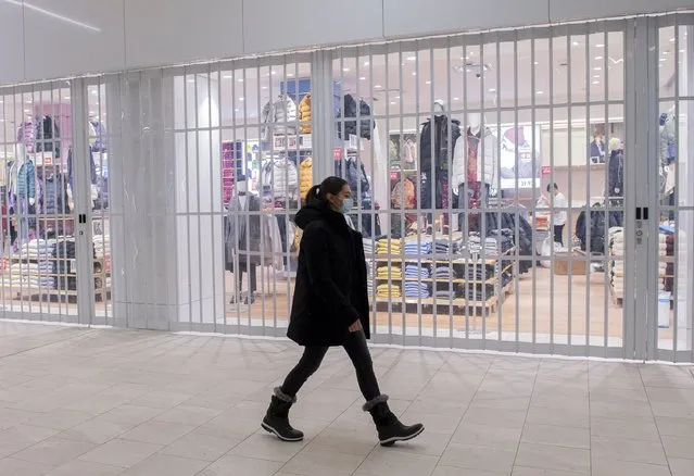 A woman walks by a closed store in a shopping mall in Montreal, Sunday, January 2, 2022, as the COVID-19 pandemic continues in Canada. Some measures put in place by the Quebec government, including the closure of stores, go into effect today to help curb the spread of COVID-19 in the province. (Photo by Graham Hughes/The Canadian Press via AP Photo)