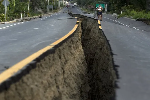 Villagers look at a rift in the highway created by a 7.8-magnitude earthquake, in Chacras, Ecuador, Tuesday, April 19, 2016. (Photo by Rodrigo Abd/AP Photo)