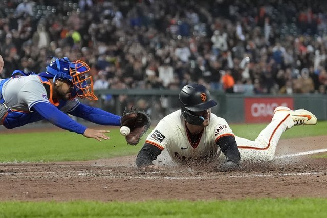 San Francisco Giants' Michael Conforto, right, slides home to score past New York Mets catcher Omar Narváez during the fifth inning of a baseball game in San Francisco, Tuesday, April 23, 2024. (Photo by Jeff Chiu/AP Photo)