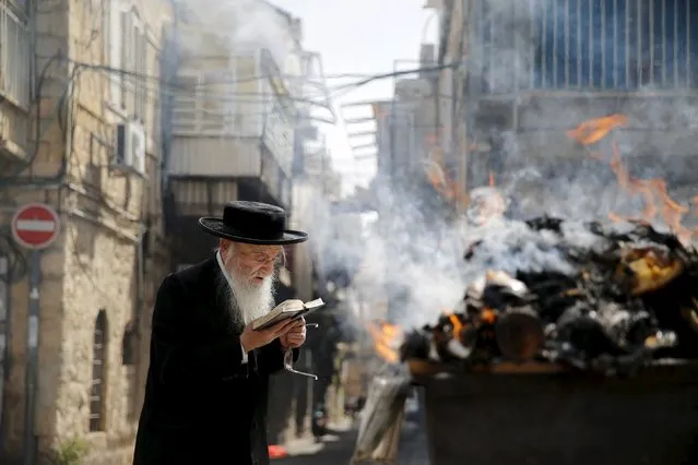 An Ultra-Orthodox Jewish man prays before burning leaven in the Mea Shearim neighbourhood of Jerusalem ahead of the Jewish holiday of Passover, April 22, 2016. Jews are forbidden to eat leavened foodstuffs during the Passover holiday that celebrates the biblical story of the Israelites' escape from slavery and exodus from Egypt. (Photo by Ammar Awad/Reuters)