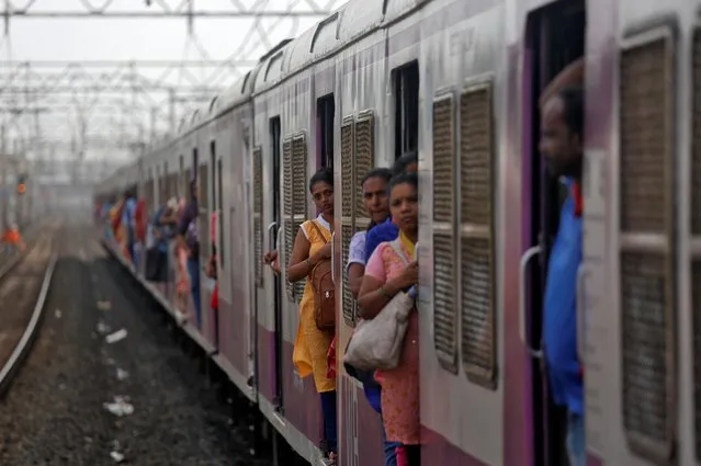 Women commuters travel by a suburban train as they head toward their destination in Mumbai, India, July 5, 2019. (Photo by Francis Mascarenhas/Reuters)