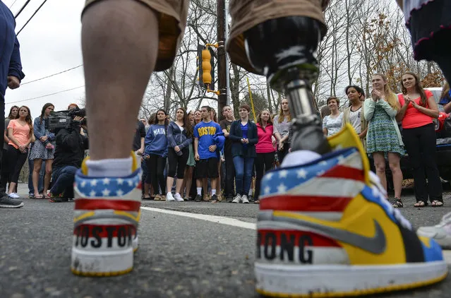 J. P. Norden stands on the pavement as he's greeted by students from Ashland High School while walking in the 1st Annual Legs for Life Walk on April 15, 2014 in Ashland, Ma. The fund raising walk was put together by the Norden family, whose two sons, J.P. and Paul Norden lost their right legs during the Boston Marathon bombing in 2013. The walk took place on the exact Boston Marathon route on the first anniversary of the Boston Marathon bombing. (Photo by Ricky Carioti/The Washington Post)