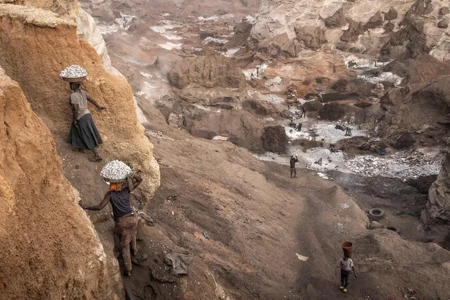 Women carry pans of granite up the side of Pissy Granite Mine in the centre of Ouagadougou on January 28, 2022. (Photo by John Wessels/AFP Photo)