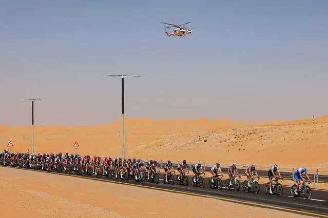 Helicopters fly above the peloton as it rides during during the first stage of the UAE cycling tour in Madinat Zayed (Zayed City) in the Gulf emirate of Abu Dhabi on February 20, 2022. (Photo by Giuseppe Cacace/AFP Photo)
