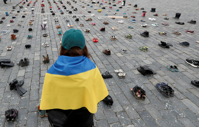 A woman looks at shoes symbolising war crimes committed against Ukrainian civilians at the Old Town Square to mark the one-year anniversary of the Russian invasion of Ukraine, in Prague, Czech Republic on February 15, 2023. (Photo by David W. Cerny/Reuters)