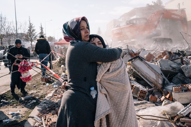 Two women embrace as rescue workers search through the rubble in Adiyaman, Turkey, on February 8, 2023. (Photo by Alice Martins/For The Washington Post)