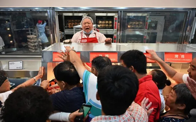 People try to get a roast chicken at the first Costco outlet in China, on the stores opening day in Shanghai on August 27, 2019. China has proved a brutal battleground for overseas food retailers in recent years, with many failing to understand consumer habits and tastes as well as local competitors building a stronger presence. (Photo by Hector Retamal/AFP Photo)