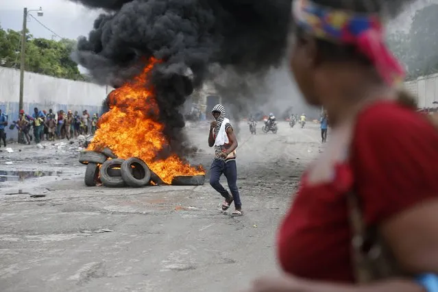 A demonstrator walks past a burning barricade during a protest against the ratification of interim Prime Minister Jean Michel Lapin, in Port-au-Prince, Haiti, Thursday, May 30, 2019. (Photo by Dieu Nalio Chery/AP Photo)