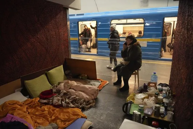 A woman with her belongings and food, sits on a chair in an improvised shelter in a subway while a train passes by in Kyiv, Ukraine, Sunday, March 13, 2022. (Photo by Efrem Lukatsky/AP photo)