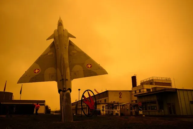 A former Swiss Air Force jet fighter Mirage 2000 manufactured by Dassault Aviation is placed on display in front of the entrance of the Swiss Army at Payerne Air Base as Sahara sand colours the sky in orange and creates a special light atmosphere, Switzerland, Tuesday, March 15, 2022. (Photo by Laurent Gillieron/Keystone)