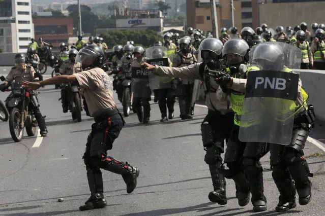 Police officers charge an anti-government protesters in Caracas, Venezuela, Monday, April 24, 2017. Thousands of people shut down the capital city's main highway to express their disgust with the socialist administration of President Nicolas Maduro. Demonstrators in least a dozen other cities also staged sit-ins as the protest movement is entering its fourth week. (Photo by Fernando Llano/AP Photo)