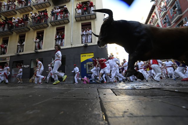 Revelers run with bulls from La Palmosilla ranch during the first day of the running of the bulls at the San Fermín fiestas in Pamplona, Spain, Sunday, July 7, 2024. People test their speed and bravery by dashing with six fighting bulls through the streets of the northern Spanish city of Pamplona. (Photo by Alvaro Barrientos/AP Photo)