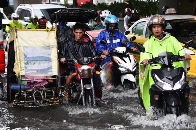 Motorists ride through a flooded street in Manila on July 23, 2024, amid heavy rains brought about by Typhoon Gaemi. (Photo by Ted Aljibe/AFP Photo)