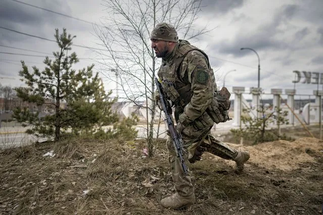 A Ukrainian serviceman takes a shooting position as he looks at approaching vehicles in Irpin, on the outskirts of Kyiv, Ukraine, Wednesday, March 9, 2022. (Photo by Vadim Ghirda/AP Photo)