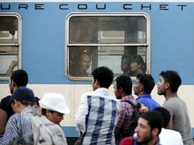 Passengers look at migrants pushing to enter an international train traveling from Thessaloniki to Budapest at Gevgelija train station in Macedonia, near the border with Greece,  July 19, 2015. (Photo by Ognen Teofilovski/Reuters)