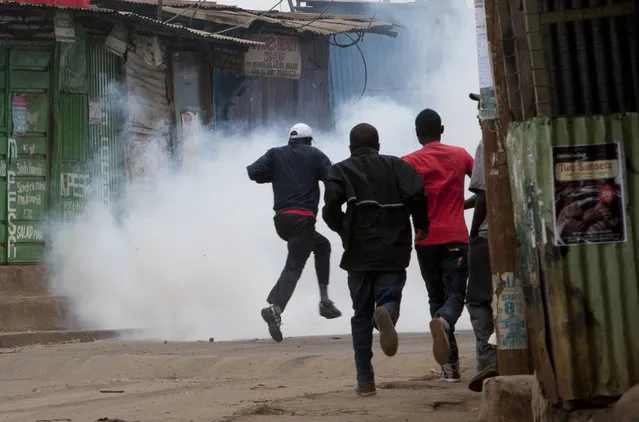 Opposition supporters, flee from exploding tear gas grenades fired by riot police, during a protest in Kibera Slums, Nairobi, Kenya Monday, May 23, 2016. (Photo by Sayyid Azim/AP Photo)