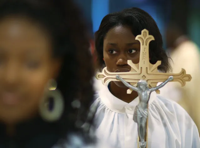 Brianna Francois carries the cross during a service at the Notre Dame D'Haiti Catholic Church as they celebrate Haitian Flag day in the Little Haiti neighborhood on May 18, 2017 in Miami, Florida. The prayer service also touched on the church's concern about the outcome of the decision on extending the Temporary Protected Status for Haitians living in the United States because it would possibly mean friends and families would be sent back to Haiti. 50,000 Haitians have been eligible for TPS and now the Trump Administration has until May 23 to make a decision on extending TPS for Haitians or allowing it to expire on July 22, which would mean possible deportation for the current TPS holders. (Photo by Joe Raedle/Getty Images)