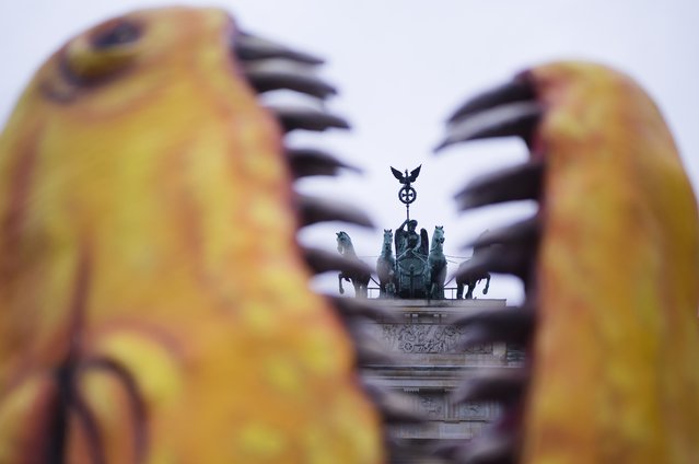 The Quadriga on top of the Brandenburg gate is photographed through the mouth of a mock-up dinosaur, set-up by Greenpeace in front of the landmark during a rally marking the nuclear shutdown in Germany in Berlin, Germany, Saturday, April 15, 2023. Germany is shutting down its last three nuclear power plants on Saturday, April 15, 2023, as part of an energy transition agreed by successive governments. (Photo by Markus Schreiber/AP Photo)