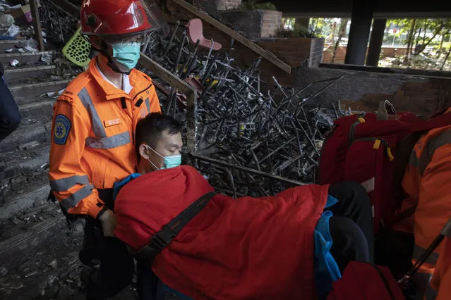 A man is evacuated by medics past charred debris from the Polytechnic University in Hong Kong on Wednesday, November 20, 2019. Hong Kong schools have reopened after a six-day shutdown but students were facing transit disruptions as the last protesters remained holed up on a university campus. (Photo by Ng Han Guan/AP Photo)