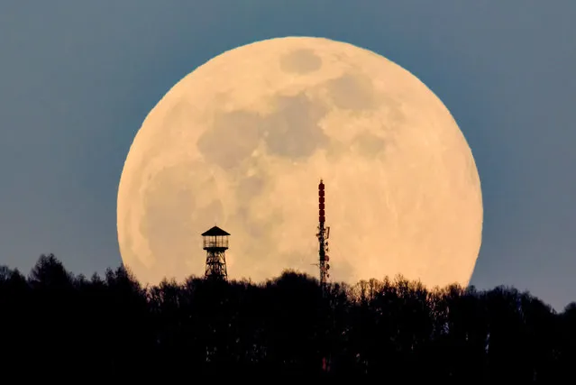 A lookout tower (L) and the broadcast tower of Antenna Hungaria at the top of Karancs mountain are backdropped by the rising moon as seen from the vicinity of Karancskeszi village, 128 kms northeast of Budapest, Hungary, 20 March 2019. (Photo by Peter Komka/EPA/EFE)