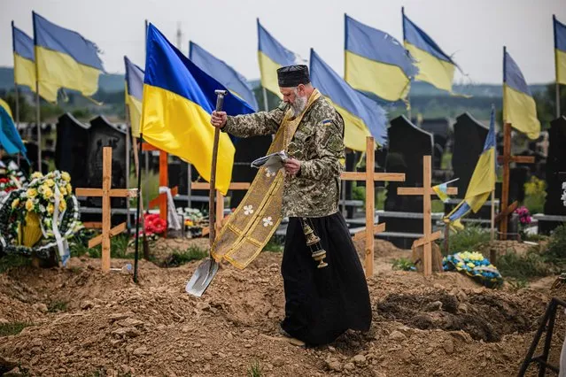A military chaplain leads a funeral service for Ukrainian servicemen Sergeii Profotilov and Igor Malenkov, both killed in the village of Vilkhivka during the Russian invasion of Ukraine, in the military section of the Kharkiv cemetery number 18 in Bezlioudivka, eastern Ukraine on May 21, 2022. (Photo by Dimitar Dilkoff/AFP Photo)
