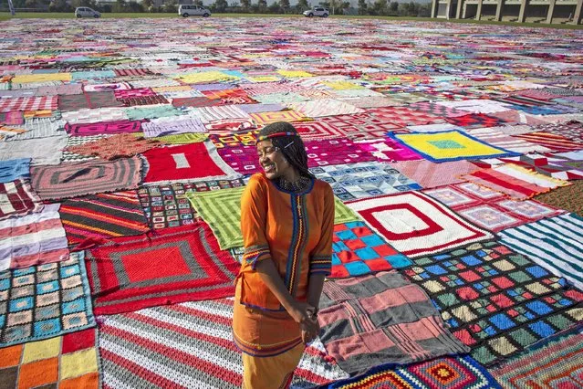 A performer stands in front of the thousands of knitted blankets on the school field at Steyn City to mark the upcoming Nelson Mandela Day as part of the 67 Blankets for Nelson Mandela Day project in Johannesburg, South Africa, 11 May 2021. The project sees thousands of blankets being knitted by “knitwits” and then given to those who need them during the cold winter in South Africa. Blankets are given away to those in need after the event. This year's event honored medical staff and first responders in the country for their work during the Covid-19 coronavirus crisis. (Photo by Kim Ludbrook/EPA/EFE)