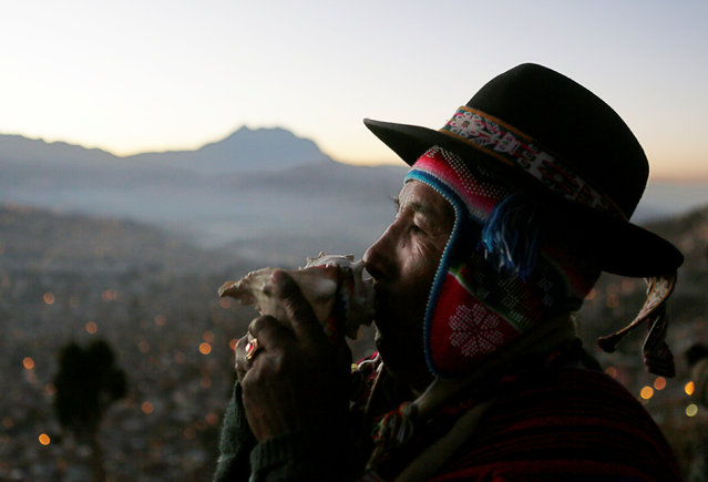 An Aymara witch doctor makes sounds with a seashell during a ceremony in El Alto near La Paz, Bolivia, June 21, 2016. (Photo by David Mercado/Reuters)