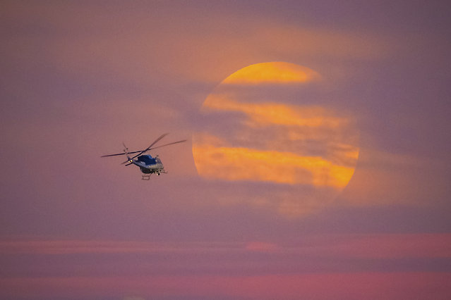 A U.S. Park Police helicopter flies past the rising full moon as it banks over the National Mall in Washington, Saturday evening, July 8, 2017. (Photo by J. David Ake/AP Photo)