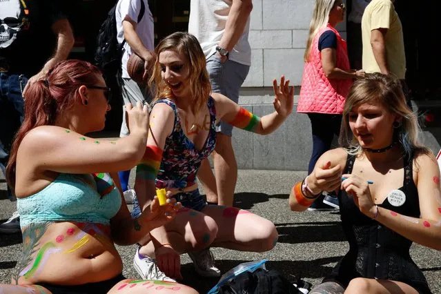 Shannon Trichler, left, Esther Dovgopolaya, and Madison Greinke, right, paint themselves before the start of the Seattle Pride Parade in Seattle, Washington, Sunday, June 26, 2016. (Photo by Sy Bean/The Seattle Times)