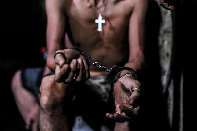 A suspected drug user is handcuffed during a night time raid on a drug den on June 16, 2016 in Manila, Philippines. The president-elect of the Philippines, Rodrigo Duterte, declared a war on crime and drugs after sweeping an election on May 9 and has been living up to his nickname, “the punisher”. Philippine police have been conducting night raids almost on a daily basis and revived a curfew for minors that had not been enforced for years, rounding up minors drinking on the streets. Based on local reports, there has been at least 59 drug-related deaths since the election and hundreds of drug suspects arrested over one month as Duterte reassured police on his full support if they killed criminals who resisted with violence. (Photo by Dondi Tawatao/Getty Images)