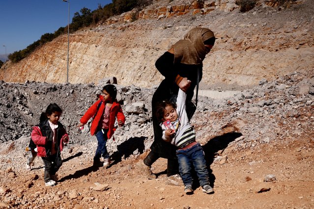 A woman walks with children while crossing from Lebanon into Syria on foot at the Masnaa border crossing, after an Israeli strike, as they flee the ongoing hostilities between Hezbollah and Israeli forces, in Al Masnaa, Lebanon on October 27, 2024. (Photo by Yara Nardi/Reuters)