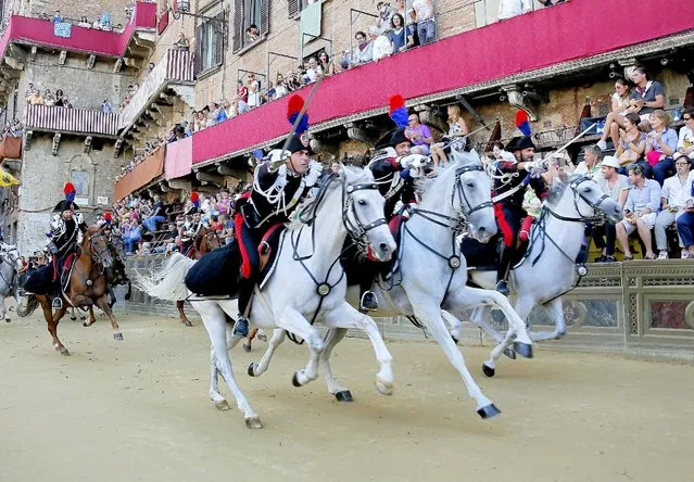 Italy's Carabinieri perform an attack before the Palio di Siena horse race in Siena August 17, 2015. Jockey Giovanni Atzeni of “Selva” parish on the horse “Polonski” won the race. Every year on July 2 and August 16, almost without fail since the mid-1600s, 10 riders compete bareback around Siena's shell-shaped central square in a bid to win the Palio, a silk banner depicting the Madonna and child. The race was postponed to August 17, 2015 due to rain. (Photo by Fabio Muzzi/Reuters)