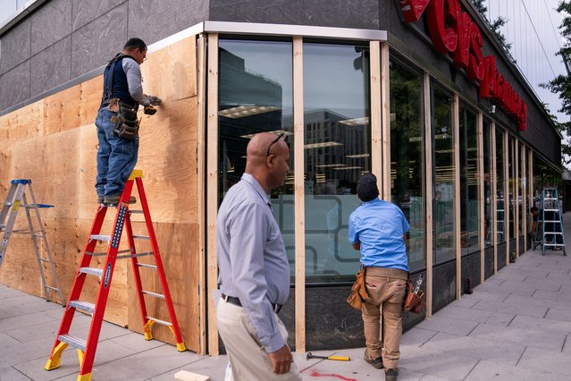 Workers cover the windows of a pharmacy near the White House with plywood ahead of the presidential election in Washington on November 4, 2024. (Photo by Nathan Howard/Reuters)