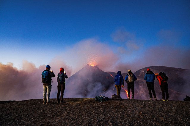 People look on as lava rises from a crater of Mount Etna, Europe's most active volcano, Italy, July 2, 2024. (Photo by Giuseppe Di Stefano/Etna Walk via Reuters)