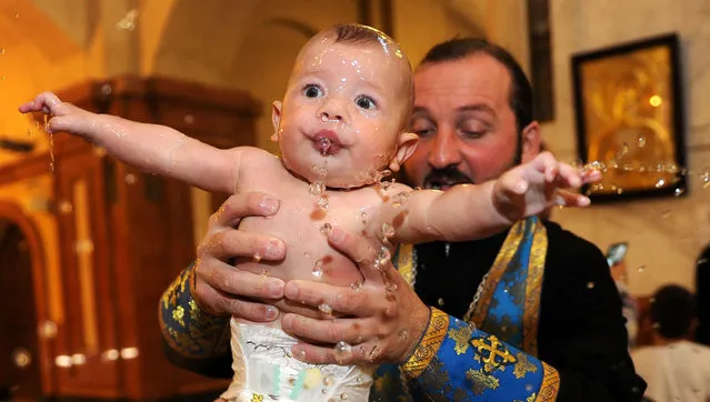 A Georgian Orthodox priest baptises a baby during a mass baptism ceremony at the Holy Trinity Cathedral in Tbilisi, on July 13, 2016. (Photo by Vano Shlamov/AFP Photo)