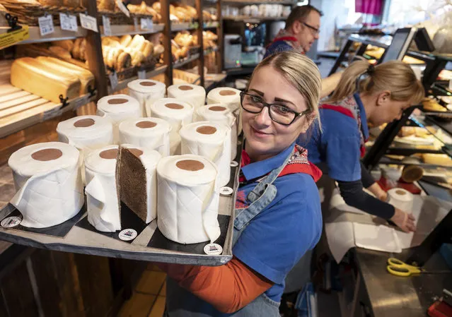 A saleswoman of the bakery Schuerener Backparadies shows a tray with round marble cakes wrapped in fondant that look like toilet paper rolls in Dortmund, Germany,  Wednesday, March 25, 2020. The toilet paper cake has become a “bestseller” during the Corona crisis. (Photo by Bernd Thissen/dpa via AP Photo)