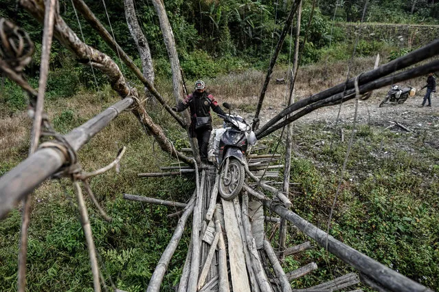 This photo taken on February 7, 2020 shows motorcycle riders preparing to cross a bridge as they travel in Lahe township in Myanmar's Sagaing region. (Photo by Ye Aung Thu/AFP Photo)